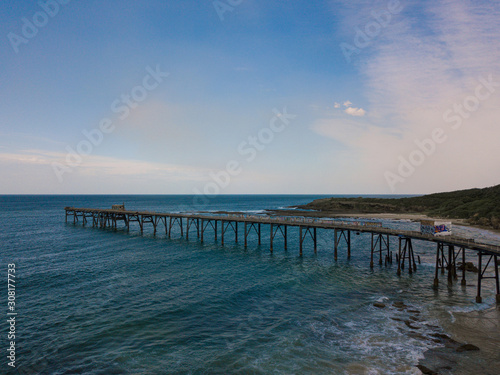 Fototapeta Naklejka Na Ścianę i Meble -  A long jetty on the coastline with blue sunny sky.