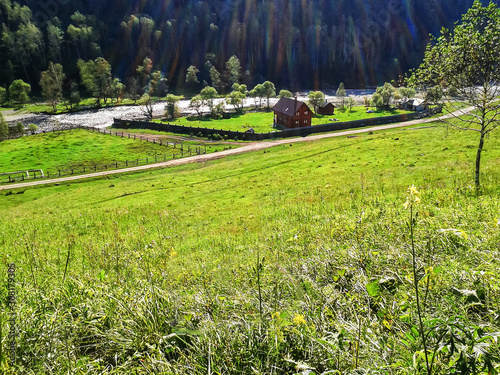 Fotografi A house by the river in a mountain valley consecrated by the sun.
