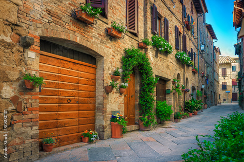 Cute narrow street decorated with flowers in Pienza, Tuscany, Italy