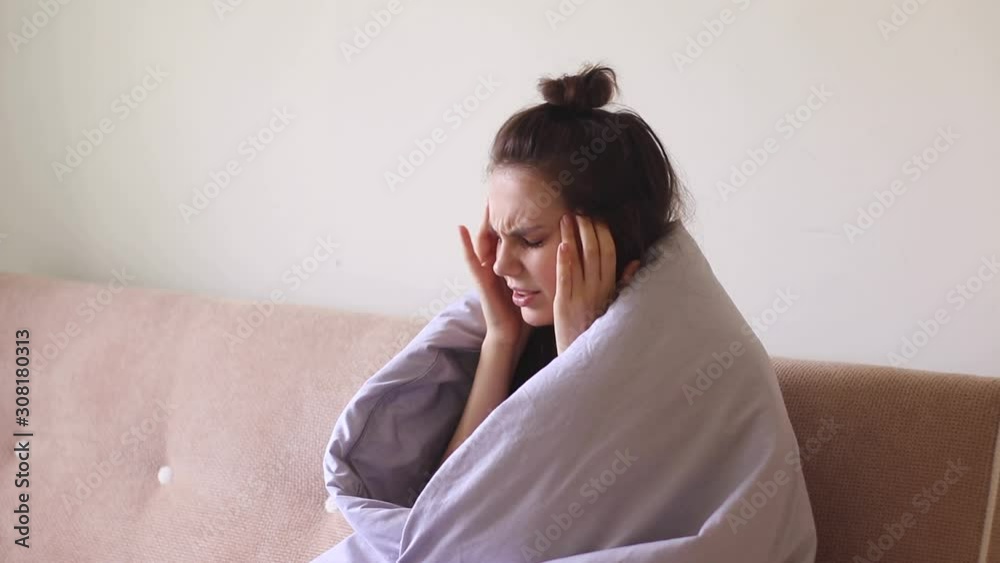 Sick young woman sitting at home with severe headache Sick young woman sitting at home with severe headache