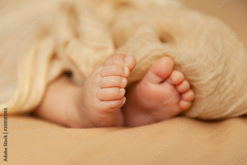 Closeup of baby feet, newborn toes on a beige background, maternity and babyhood concept Closeup of baby feet, newborn toes on a beige background, maternity and babyhood concept