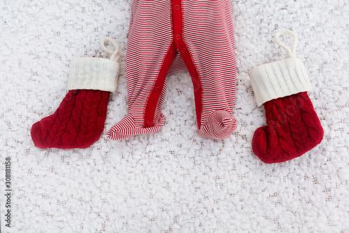 Newborn legs with Christmas socks on a white blanket as a background