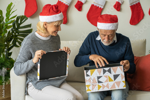 Senior couple open big gift presents box and happy together at home for Christmas festival day, Retirement lifestyle concept