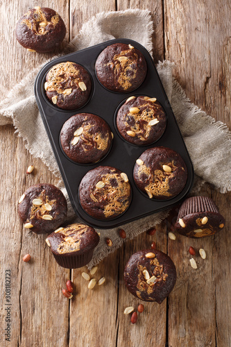 Freshly baked chocolate muffins with peanut butter and nuts in a baking dish. Vertical top view