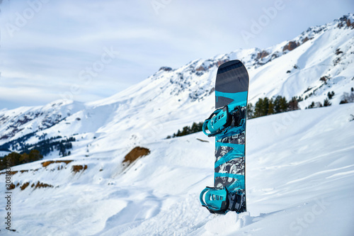 snowboard stuck in snow on a background of snowy mountains