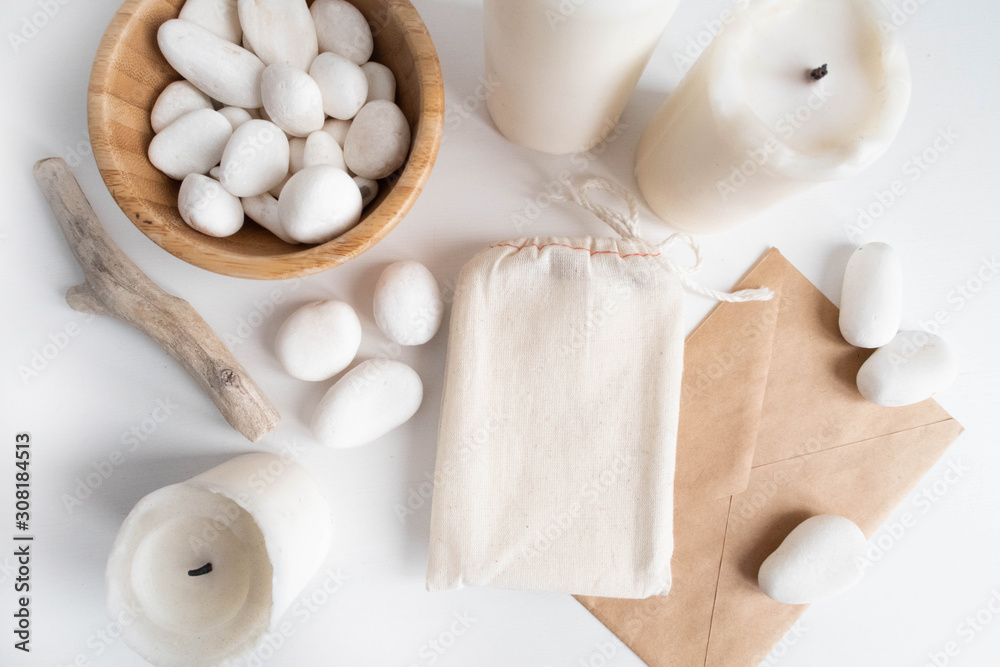 Mock up of cotton bag or pouch and bowl with white pebble and boho elements on white table. Boho design of tarot cards deck pouch on white table with copy space for your image or text