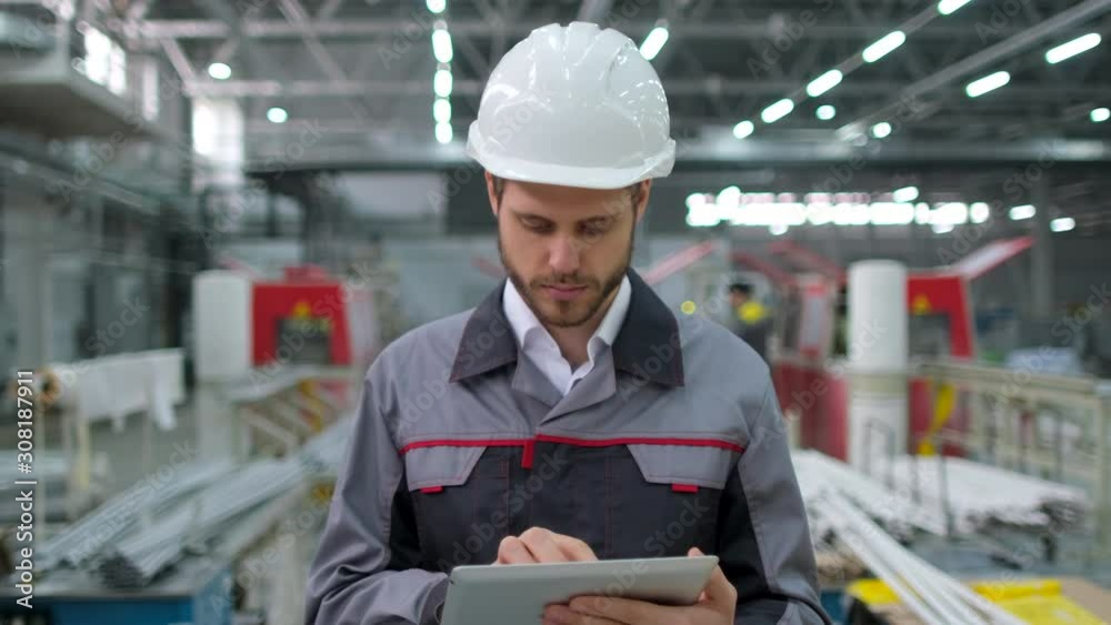Caucasian young bearded professional male engineer man people in hard hat working on engineering industrial manufacturing facility using tablet indoors. worker architect workman contractor slow-mo 4 K Caucasian young bearded professional male engineer man people in hard hat working on engineering industrial manufacturing facility using tablet indoors. worker architect workman contractor slow-mo 4 K
