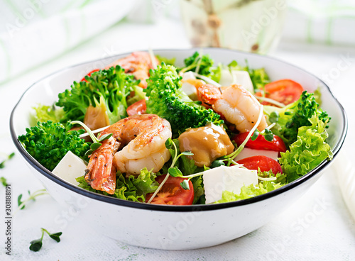 Delicious fresh salad with shrimps / prawns, broccoli, feta cheese, tomatoes, lettuce and peanut dressing. Diet menu. Top view