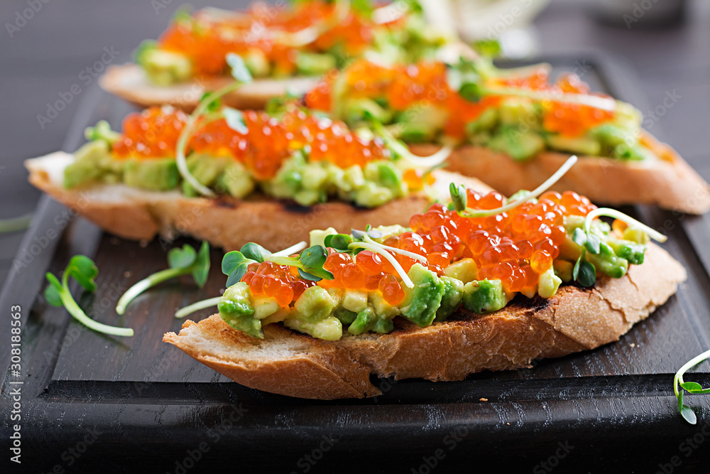Sandwiches with salmon red caviar and salsa with avocado. Sandwich for lunch. Delicious food. Sandwiches with salmon red caviar and salsa with avocado. Sandwich for lunch. Delicious food.