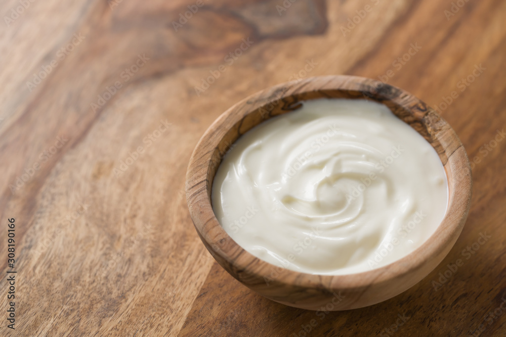 organic white yogurt in olive wood bowl on table organic white yogurt in olive wood bowl on table