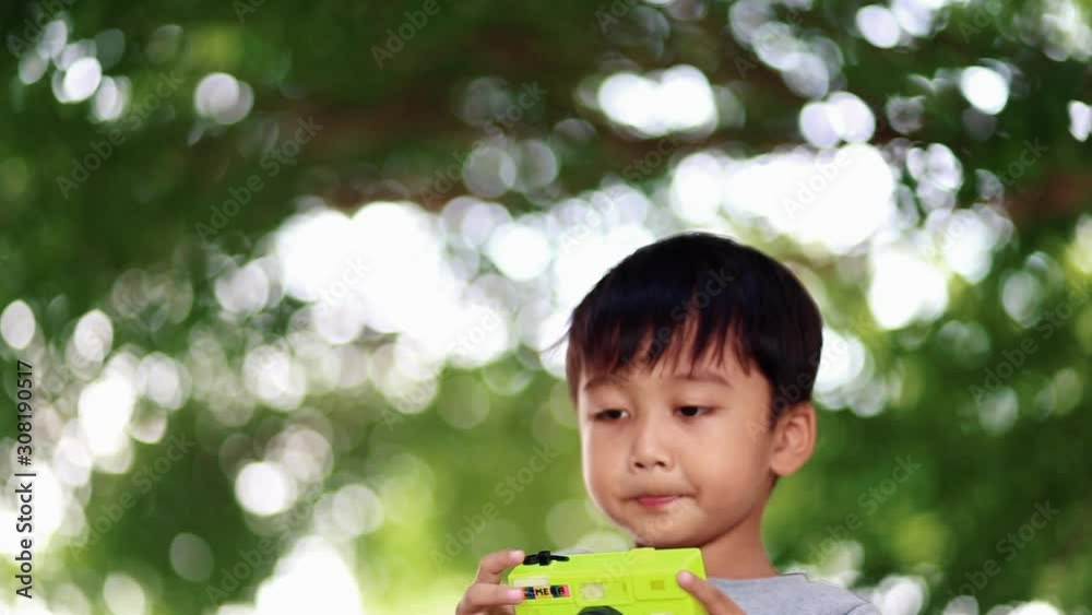 Asian child takes photo with toy camera on nature green bokeh background Asian child takes photo with toy camera on nature green bokeh background