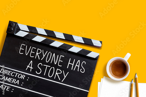 Everyone has a story.text title on movie clapper board  and coffee cup on yellow background photo