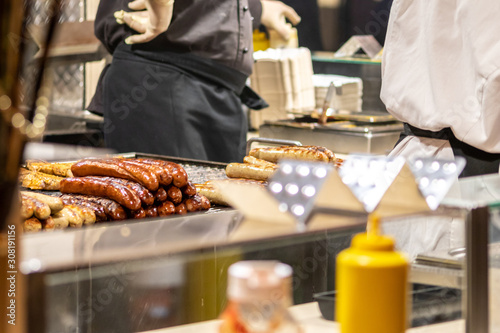 Frische leckere heiße Würstchen am Bratwurststand auf dem Weihnachtsmarkt mit Krakauern, Nürnberger Rostbratwürstchen und Senf als beliebter Snack für den Besuch auf Kirmes und Weihnachtsmarkt