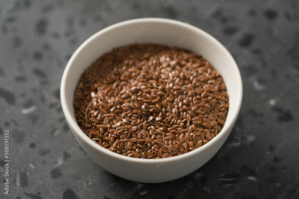 Flax seeds in white bowl on terrazzo surface closeup Flax seeds in white bowl on terrazzo surface closeup