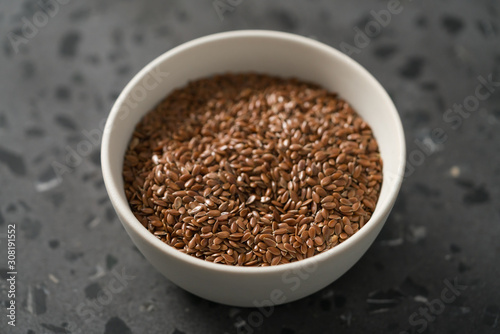 Flax seeds in white bowl on terrazzo surface closeup