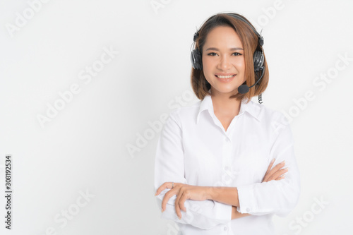 Call center operator woman short hair, wearing a white shirt with headset standing crossing her arms isolated on white background.