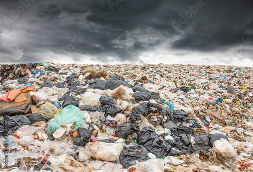 garbage dump pile in trash dump or landfill,truck is dumping the gabage from municipal,garbage dump pile and dark clouds or rain clouds background ,pollution concept.
