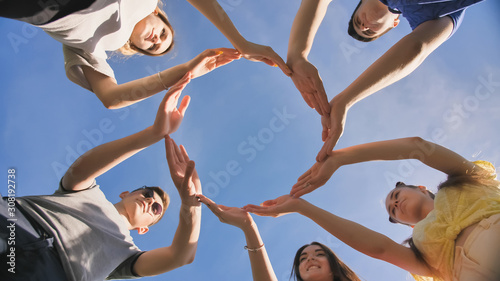 A group of friends makes a circle from the palms of their hands.