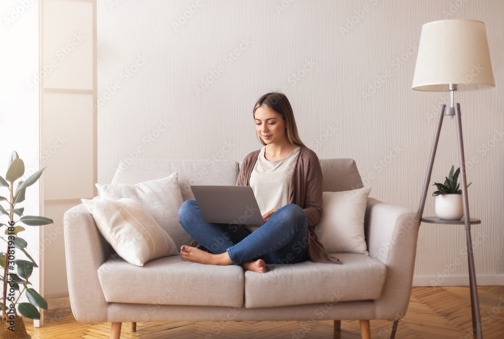 Cute young girl surfing in internet on laptop, resting on couch Cute young girl surfing in internet on laptop, resting on couch