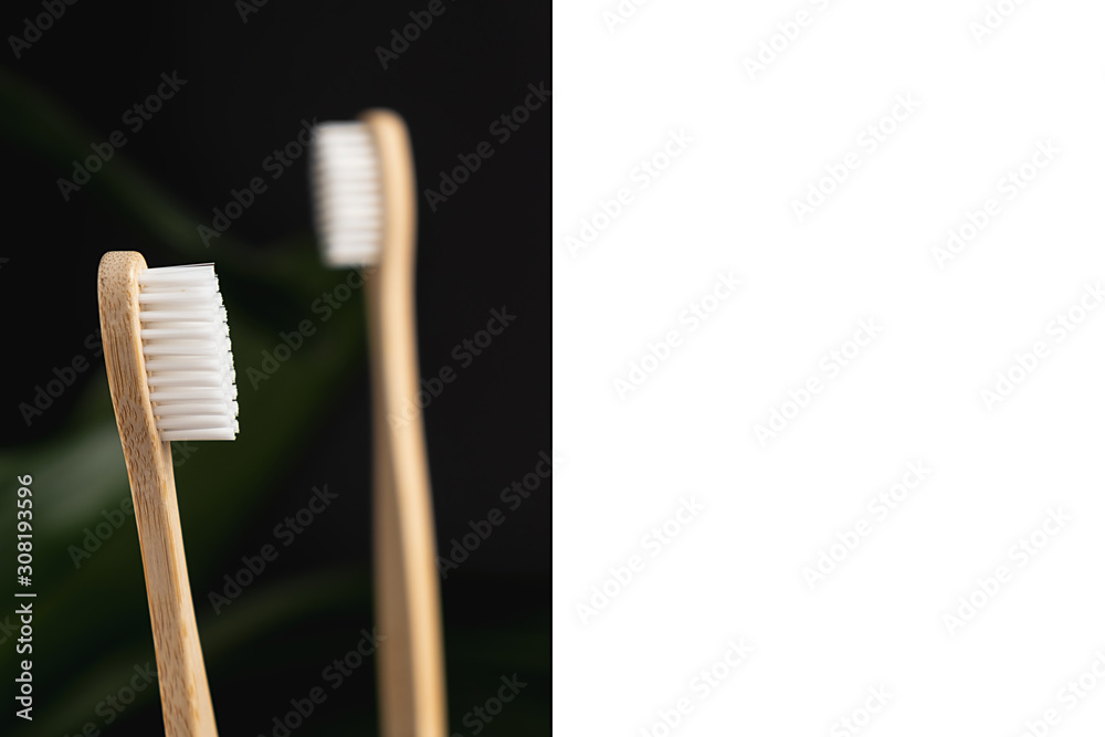 Two eco natural bamboo toothbrushes and white frame on black background. Sustainable lifestyle and zero waste home. Dental care and Eco friendly and reuse concept. Copy space