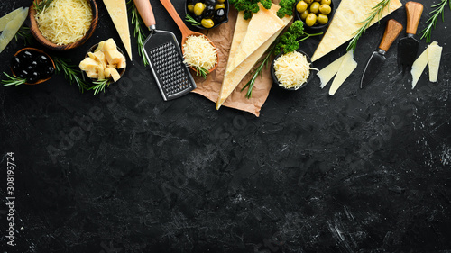 Set of hard cheeses with cheese knives on black stone background. Parmesan. Top view. Free space for your text. photo