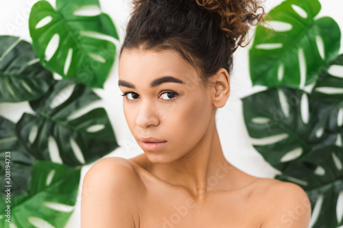 Beauty concept. Beautiful afro woman against tropical leaves