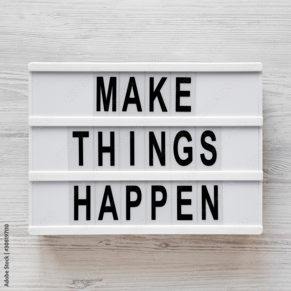 'Make things happen' words on a lightbox on a white wooden surface, top view. Overhead, from above, flat lay. Closeup.