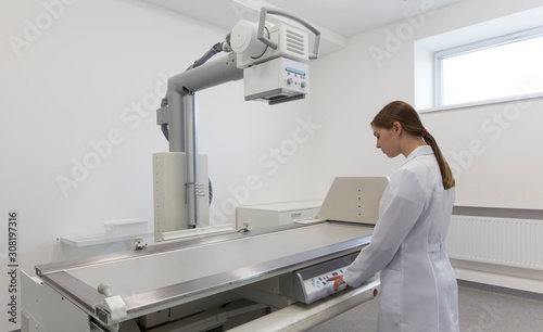 Female doctor in medical gown using X-ray machine