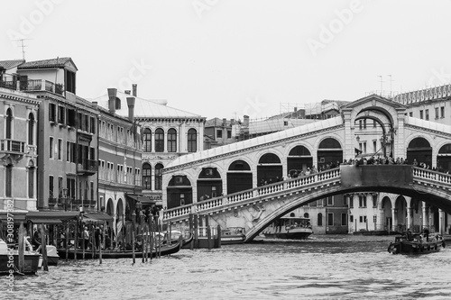 Black and white photo of the Rialto bridge taken from the Grand Canal in Venice, Italy