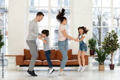 Happy mother and father with two children jumping in dance.
