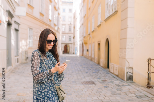 Woman talk by her smartphone in city. Young attractive tourist outdoors in italian city