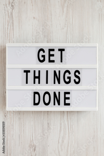 'Get things done' words on a lightbox on a white wooden surface, top view. Overhead, from above, flat lay.