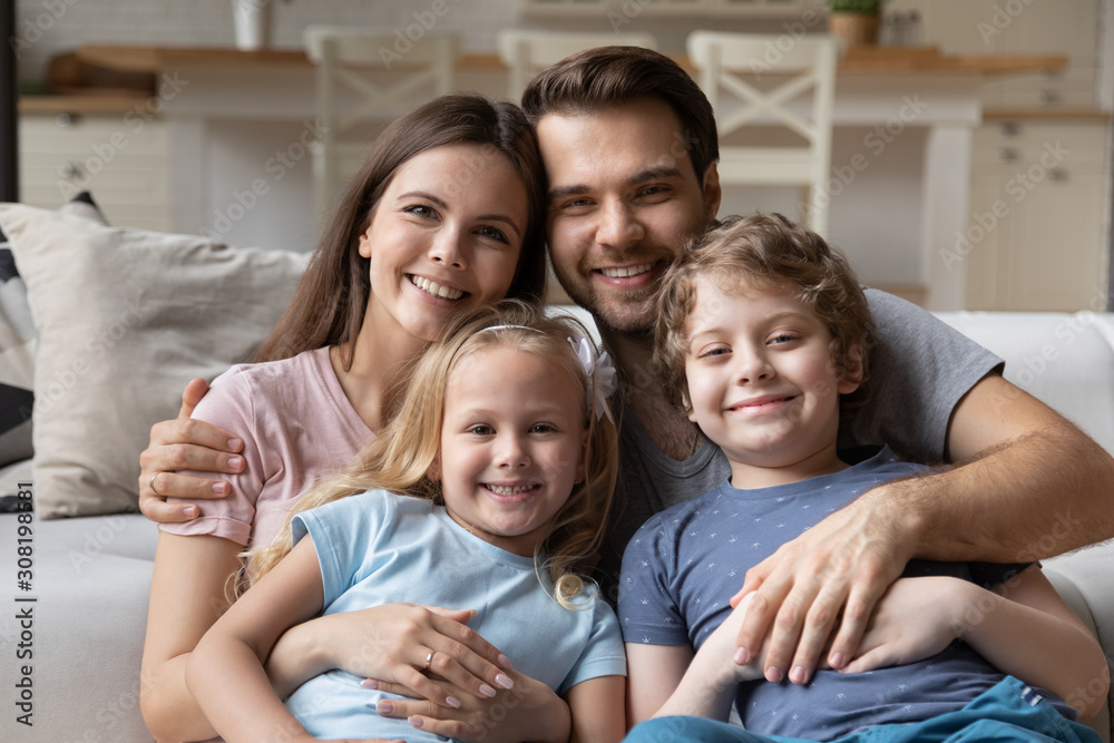 Couple and little children sitting on couch looking at camera