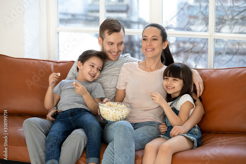 Happy young family and preschool children watching funny tv show