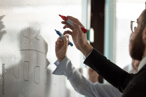 Businesspeople write on white board developing business plan together
