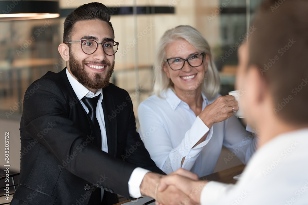Smiling multiracial business partners handshake closing deal Smiling multiracial business partners handshake closing deal
