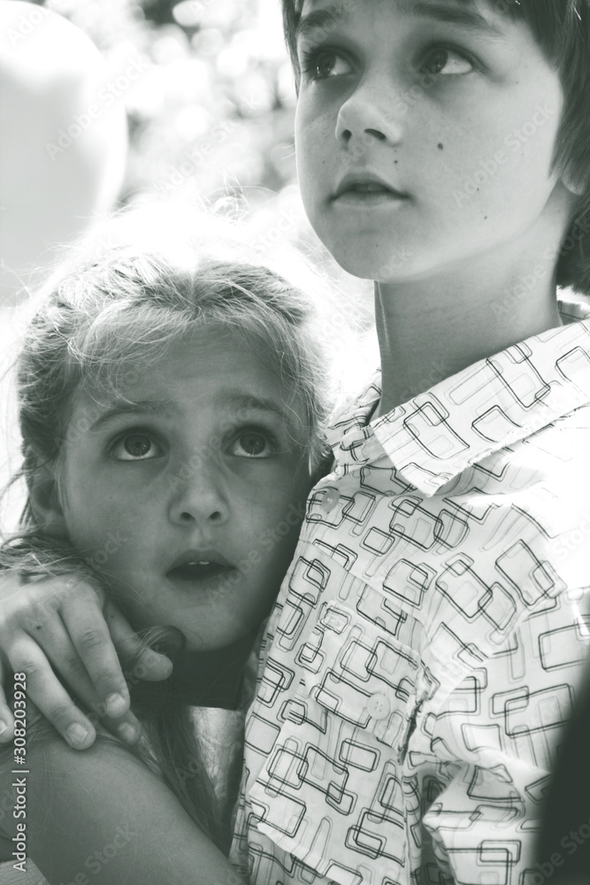 Portrait of little caucasian girl and boy in casual clothes hugging