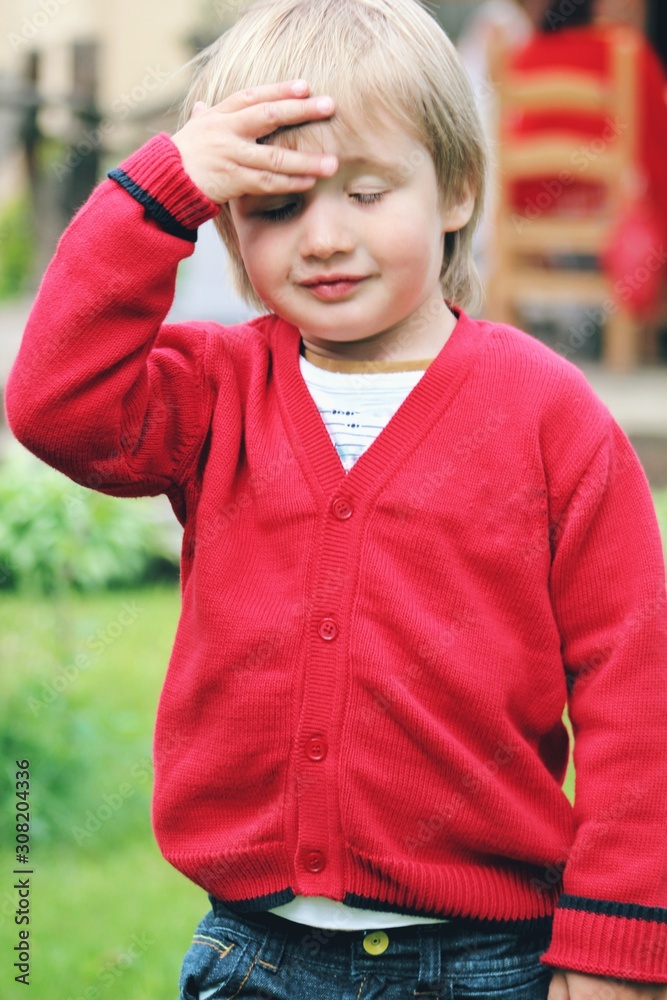 Portrait of little caucasian boy in casual clothes in home garden
