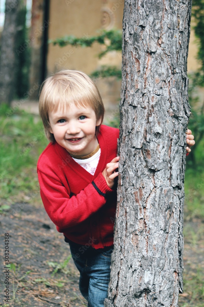 Portrait of little caucasian boy in casual clothes in home garden