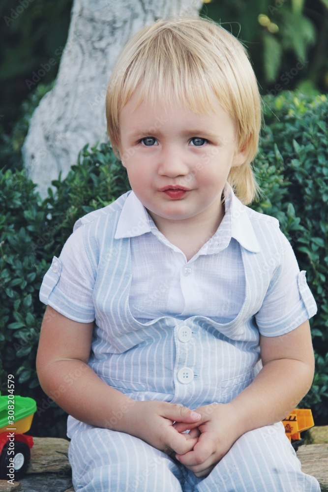 Portrait of little caucasian boy in casual clothes in home garden