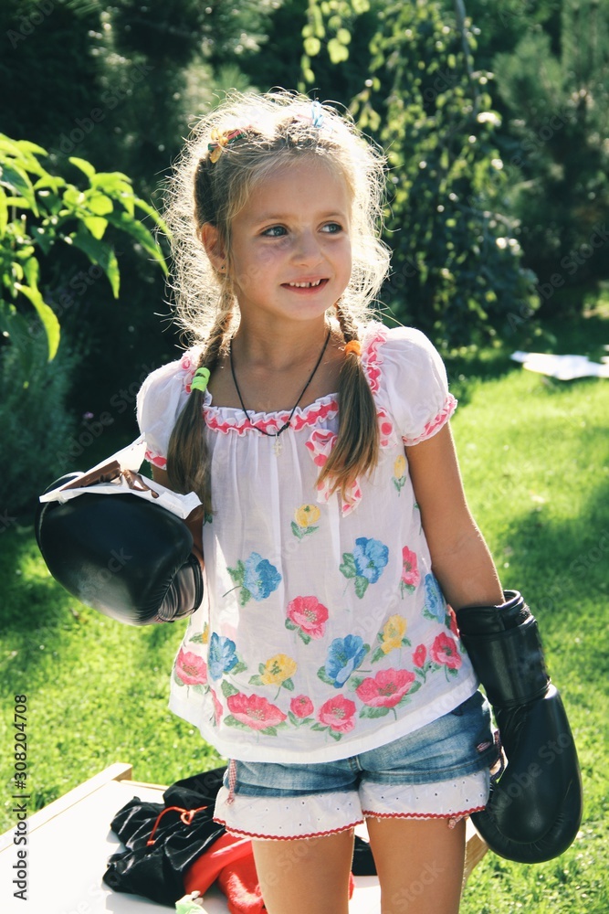 Portrait of little caucasian girl wearing boxing gloves