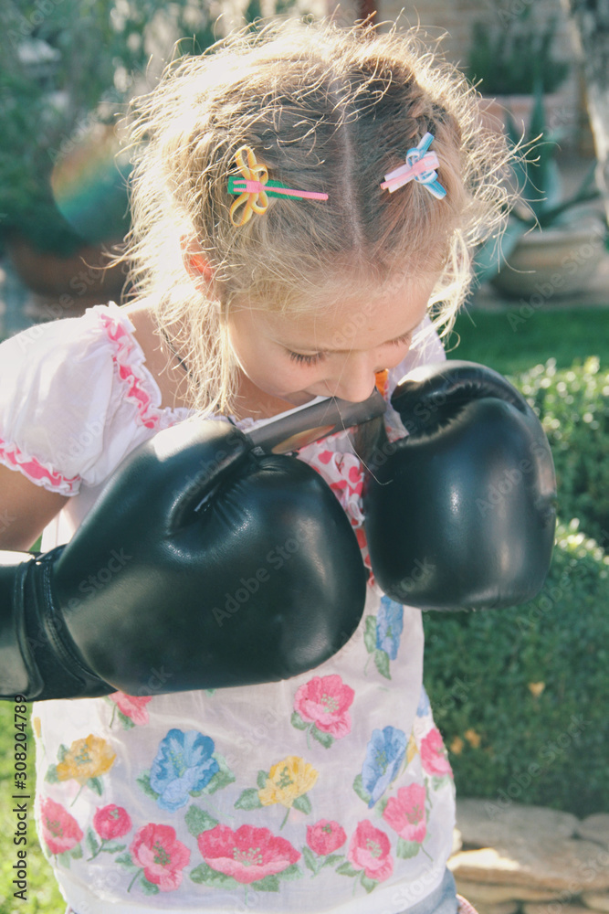 Portrait of little caucasian girl wearing boxing gloves