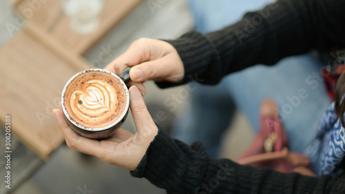 Coffee latte heart texture in hand of tourists.