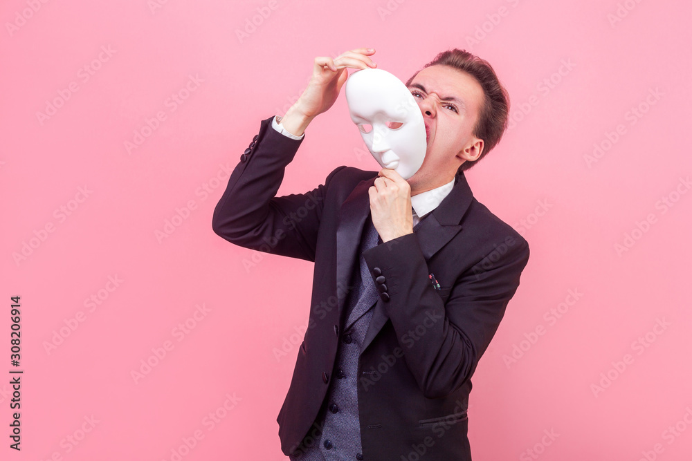Portrait of distressed businessman in elegant suit and with stylish haircut taking off his mask, expression of pain screaming fatigue on his face. indoor studio shot isolated on pink background Portrait of distressed businessman in elegant suit and with stylish haircut taking off his mask, expression of pain screaming fatigue on his face. indoor studio shot isolated on pink background