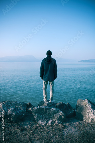 solitude man concept, depressed emotions of a person that stands alone on the shore looking the lake