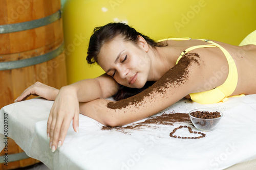 Woman brunette getting coffee scrub treatment in spa salon