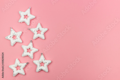 Holiday decorations. Composition made of white stars - Christmas tree toys on pink background. top view, closeup. Copy space