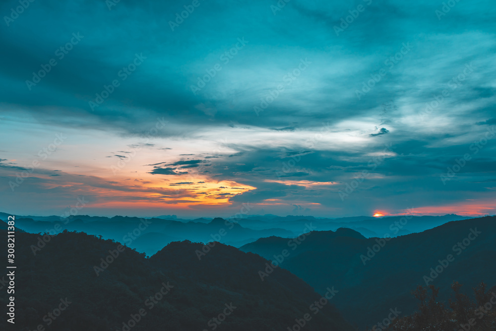 Sunset or evening time over clouds with mountain hill forest and sunlight sunrays or sunbeams on background. at 