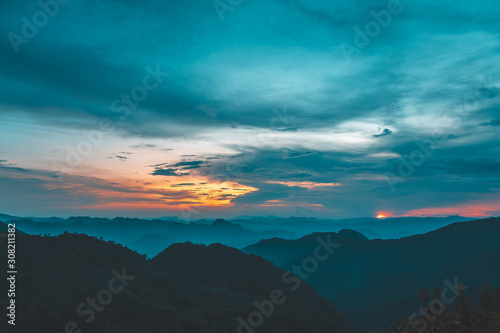 Sunset or evening time over clouds with mountain hill forest and sunlight sunrays or sunbeams on background. at "LerGuaDa" Tak province, Thailand, Asia.