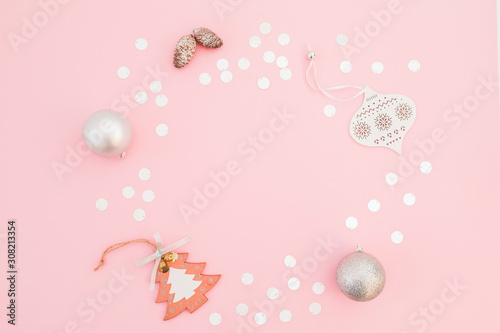 Christmas frame composition made of silver decoration and confetti on pink background. Flat lay